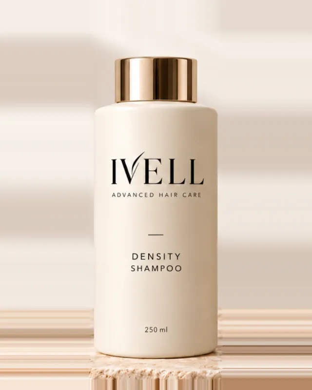 Frasco de 250 ml del champú IVELL Density, color crema con tapón dorado, sobre una piedra de travertino.