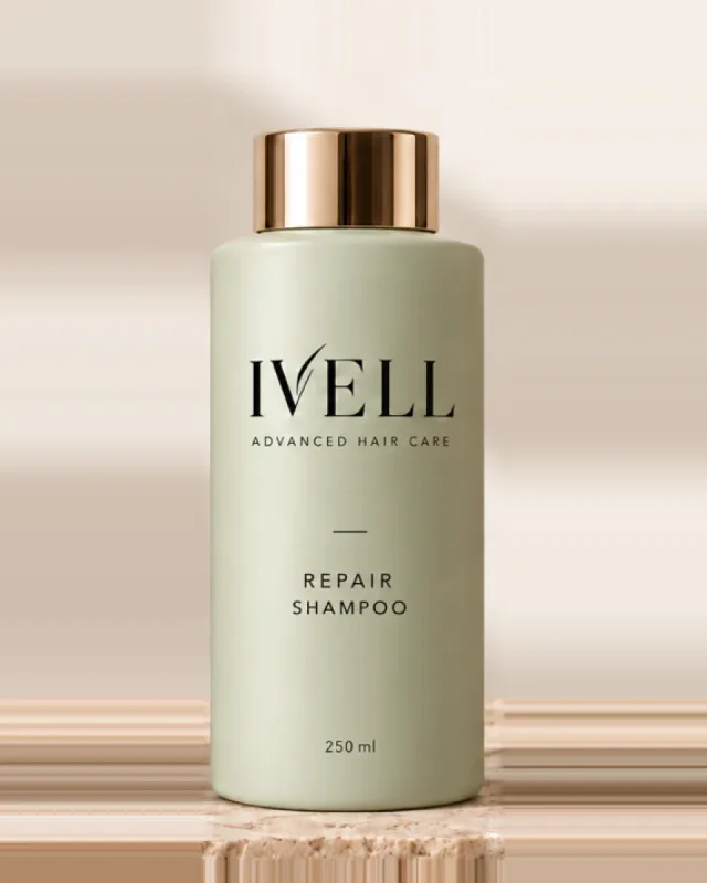 Frasco de 250 ml de IVELL Repair, color verde salvia con tapón dorado, sobre una piedra de travertino.