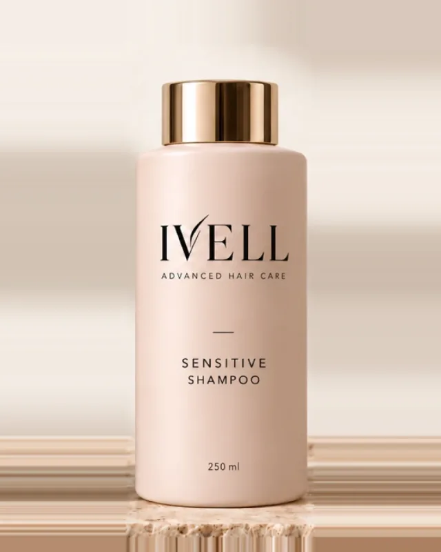 Frasco de 250 ml del champú IVELL Sensitive, color rosa empolvado con tapón dorado, sobre una piedra de travertino.